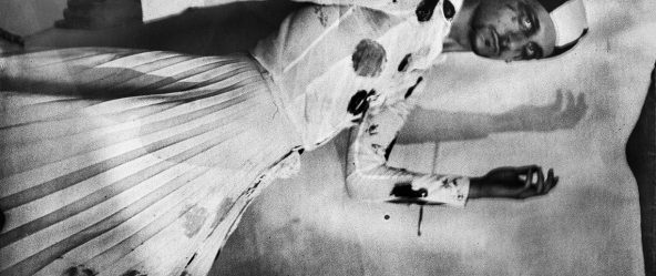 Seitliches Ganzkörperporträt mit erhobenem Arm, Badekappe, gepunkteter Faltenrock, Schattenwurf an der Wand, Kamera Mentor, ORWO Fotopapier, analoge Fotografie Meeresschnee 4