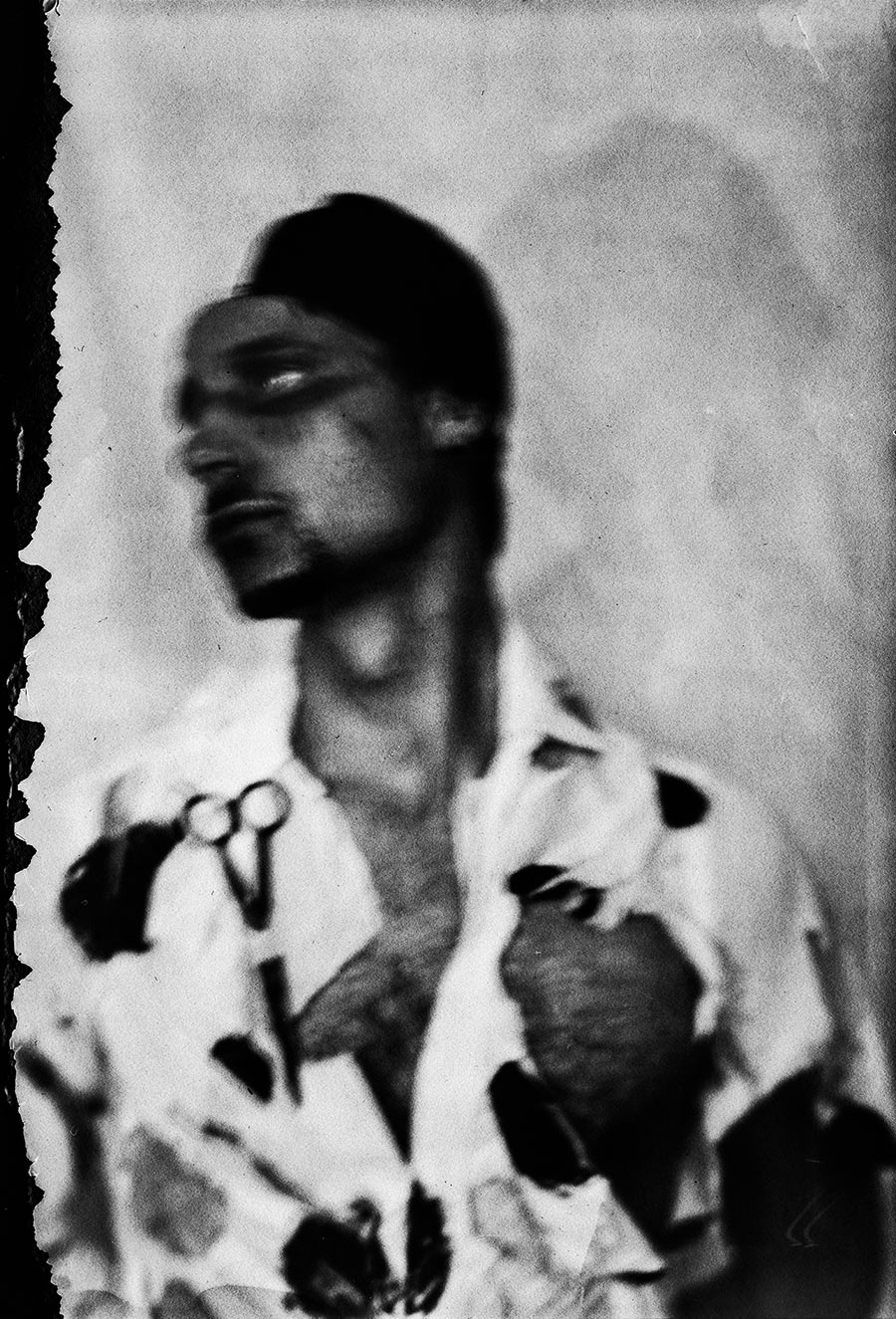 Unscharfes Profilporträt mit Schere am Hemd, dunkle Farbflecken auf weißem Stoff, Kamera Mentor, ORWO Fotopapier, analoge Bewegungsunschärfe, Meeresschnee 4