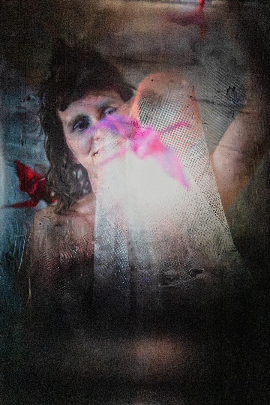 Porträt mit erhobenem Arm und Netzstoff, pink-roter Origami-Kranich, warmes Streiflicht, Leica Q through the viewfinder Mentor, Fotoserie Vogelfrei