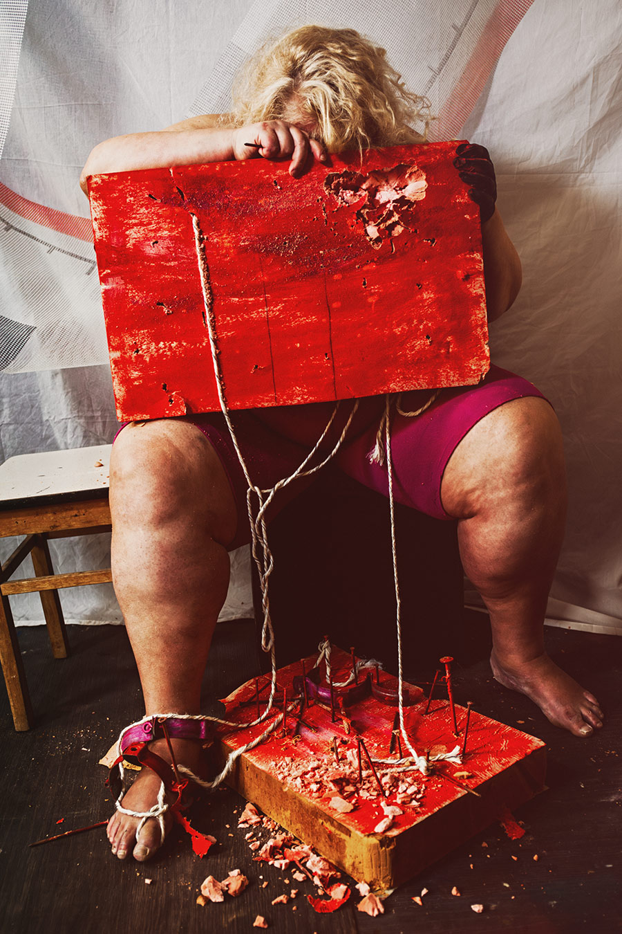 Vornübergebeugte Person mit rotem Brett auf Gesicht, gefesselter Fuß auf Nagelbrett, Canon 6D, dramatische Bondage-Fotografie gefesselte Freiheit Vogelfrei