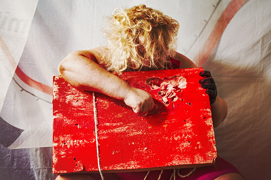 Rückenansicht mit blondem Haar über rotem Nagelbrett, Faust auf beschädigtem Holz, Canon 6D, abstrakte Bondage-Inszenierung Vogelfrei