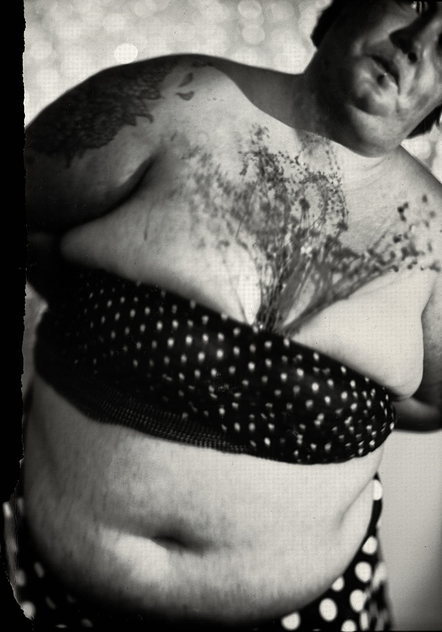 Nahaufnahme eines dicken tätowierten Oberkörpers mit Abdrücken welker Blumen, Tattoos und Hautfalten sichtbar, analoge Fotografie auf Fotopapier, clowneske Körperstudie