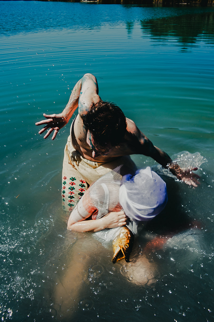 zwei figuren im wasser verschlungen, eine hält netzverhüllten kopf der anderen, dramatische fotoperformance fischtanz, canon 6d