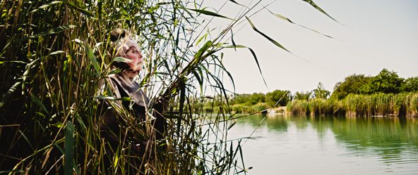 dicke frau am seeufer im schilf, blick zum wasser, ruhige naturaufnahme schwanensee-serie, canon 6d