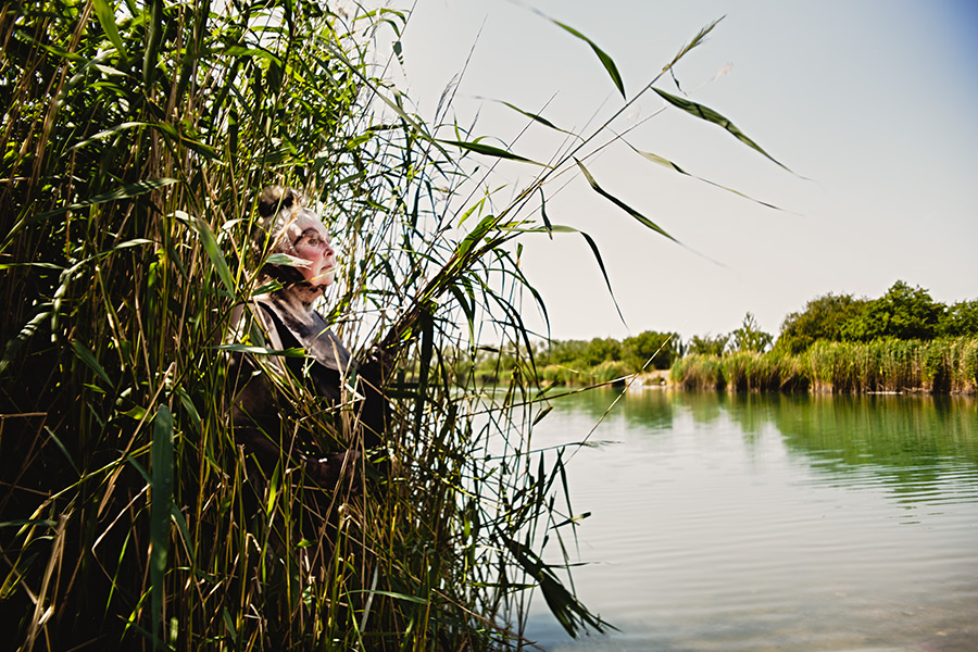 dicke frau am seeufer im schilf, blick zum wasser, ruhige naturaufnahme schwanensee-serie, canon 6d