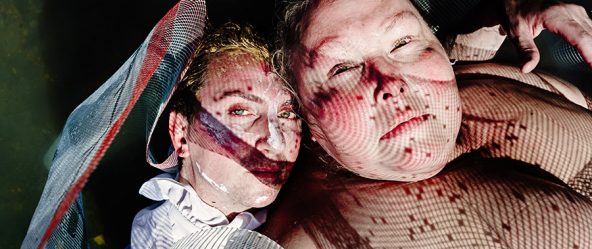 zwei gesichter kopfüber im wasser durch rotes netzmaterial fotografiert, verzerrte doppelbelichtung schwanensee-serie teil 2