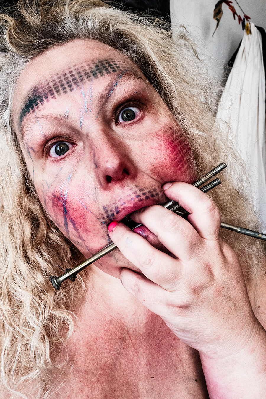 extreme nahaufnahme gesicht mit nägeln im mund, bemalte haut mit gitterlinien, expressives selbstporträt stanze-serie