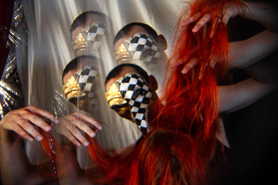 Mehrfachbelichtung mit vervielfachter Schachbrettmaske, glänzender Stoff im Hintergrund, Hände greifen ins rote Haar, konzeptuelle Fotoserie über Tod und Wiederholung