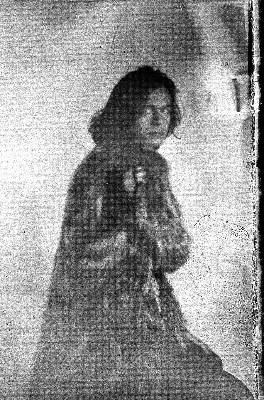 Unscharfes analoges Porträt einer Person mit langem dunklem Haar in Pelzmantel, Blick über die Schulter zur Kamera, körnige Papiernegativ-Ästhetik, Großformatkamera, Fotoserie Wolfsstunde