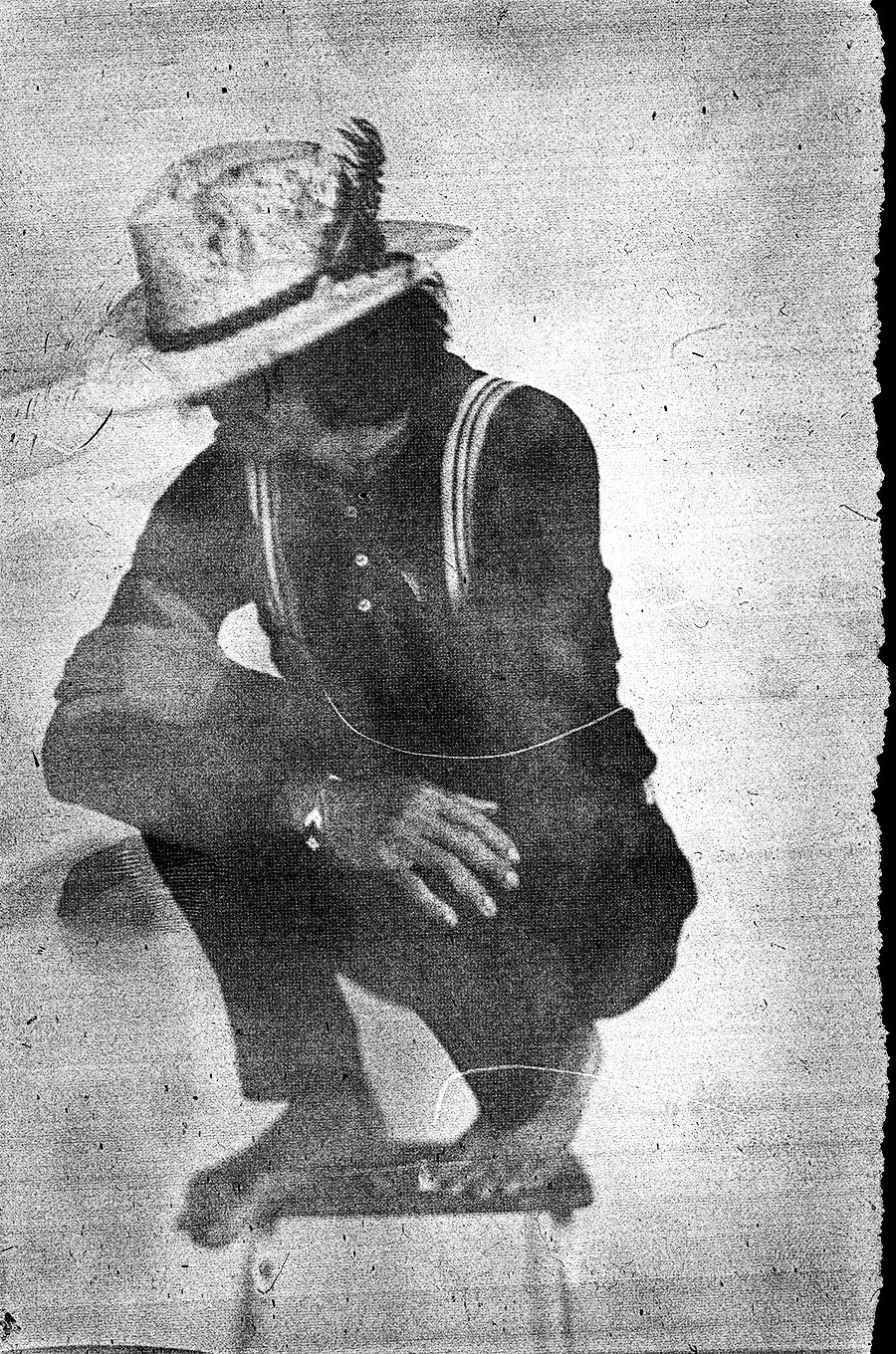 Hockende Person mit Strohhut, Gesicht im Schatten verborgen, gestreifte Hosenträger, analoges Porträt auf Papiernegativ, Großformatkamera, Fotoserie Wolfsstunde