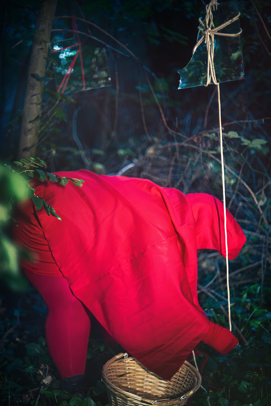 rotkäppchen gebeugt über weidenkorb wald, hängender spiegel, rotes cape, inszenierte fotografie piroska