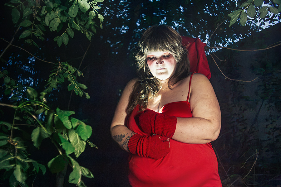 rotkäppchen sich selbst umarmend blick nach unten, rotes kleid wald, inszenierte fotografie piroska selbstliebe